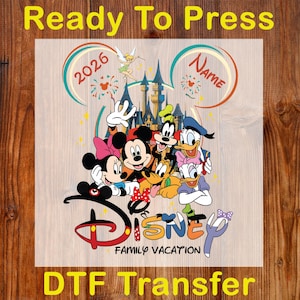 May include: DTF transfer featuring Disney characters Mickey Mouse, Minnie Mouse, Donald Duck, Goofy, and others. The design includes the text "Disney Family Vacation" and "2026", with a castle and Tinkerbell in the background. The words "Ready To Press" and "DTF Transfer" are also visible.