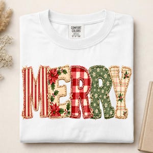 May include: A white t-shirt featuring the word MERRY in large, stitched-style letters. Each letter has a unique pattern: red and white stripes, poinsettias on cream, red and white gingham, green with white flowers, and a plaid with holly.