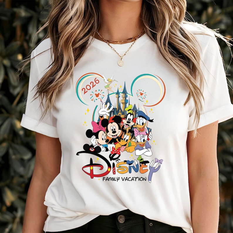 May include: White t-shirt with a Disney family vacation design. The graphic features Mickey and Minnie Mouse, Donald and Daisy Duck, Goofy, and Pluto, with the text "Disney Family Vacation" and the year "2026".