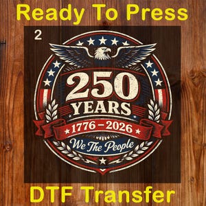 Peut inclure: Un motif de transfert DTF circulaire sur le th&egrave;me patriotique. Le motif pr&eacute;sente un aigle, des &eacute;toiles et le texte "250 YEARS 1776-2026 We The People". Le motif est de couleur rouge, blanc et bleu. Les mots "Ready To Press" et "DTF Transfer" sont &eacute;galement pr&eacute;sents.