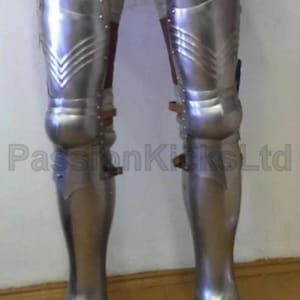 May include: Polished metal leg armor with riveted plates and pointed toe boots. The armor has brown leather accents and is designed to protect the legs. The text "PassionKicksLtd" is visible on the image.