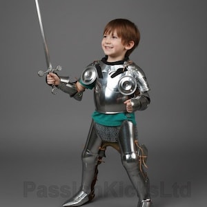 May include: A child in a full suit of shiny, silver-colored knight's armor, including a breastplate, arm and leg guards, and a helmet. The child is holding a silver sword and smiling. The armor is detailed and realistic, creating a medieval theme.