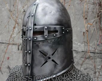 May include: A medieval-style steel helmet with riveted accents and a cross-shaped ventilation design. The helmet features a visor with horizontal eye slits and is worn over chainmail. The text "PassionKicksLtd" is visible at the bottom.