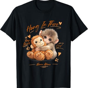May include: Black t-shirt featuring a graphic of two adorable monkeys hugging. The text "Hang In There", "Stay Strong", "You are Loved", and "Never Alone" are in orange script. Hearts and stars accent the design.