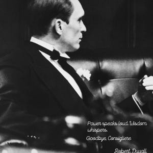 May include: Black and white photograph of a man in a tuxedo, seated and looking to the right. The image includes text that reads "Power speaks loud. Wisdom whispers. Goodbye, Consigliere. Robert Duvall 1931-2026."