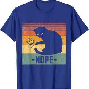 May include: Blue t-shirt with a black cat silhouette, yellow eyes, and a gold crown. The cat is above the word "-NOPE-" in white. The background has orange, yellow, and green horizontal stripes. A humorous cat-themed design.