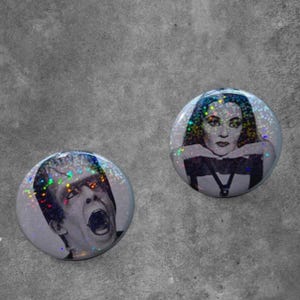 May include: Two circular pin-back buttons featuring holographic glitter overlays. One button displays a black and white portrait of a man with a flat-top hairstyle and an open mouth. The other button shows a black and white portrait of a woman.