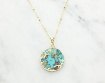 Peut inclure: Un collier en chaîne dorée avec un pendentif rond en turquoise. Le pendentif est composé de nombreuses petites pièces de turquoise serties d'or.
