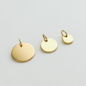 Könnte beinhalten: Drei goldfarbene Metallscheiben mit einer Öse oben. Die Scheiben haben unterschiedliche Größen, wobei die größte Scheibe in der Mitte des Bildes liegt.