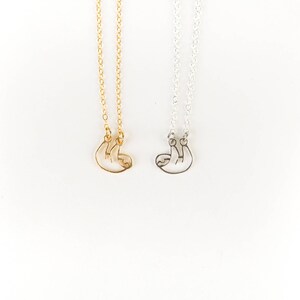 May include: Two necklaces with a sloth pendant. One necklace is gold and the other is silver.