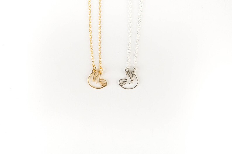 May include: Two necklaces with a sloth pendant. One necklace is gold and the other is silver.