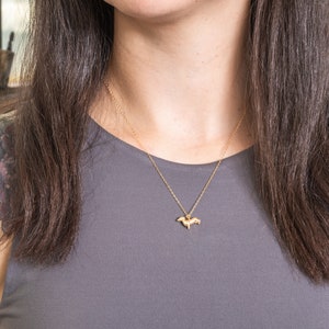 May include: A gold chain necklace with a small, detailed dachshund pendant.
