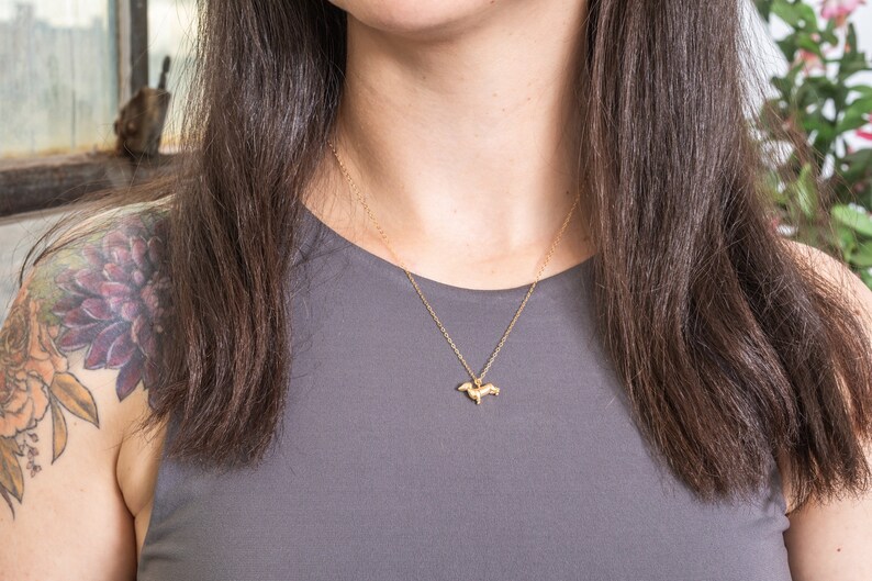 May include: A gold chain necklace with a small, detailed dachshund pendant.