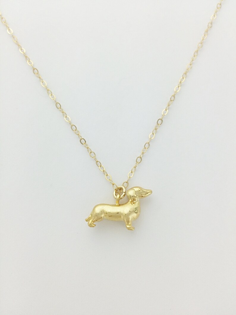 May include: A gold chain necklace with a gold dachshund pendant.