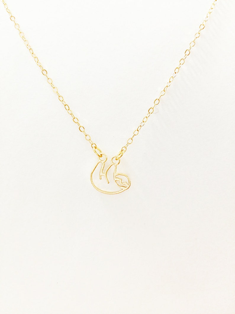 May include: A gold chain necklace with a delicate gold sloth pendant.