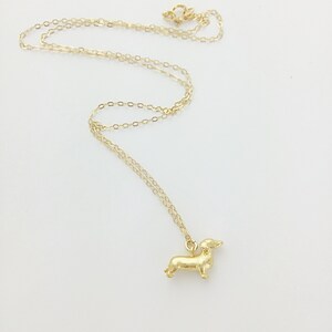 May include: A gold chain necklace with a small gold dachshund pendant.