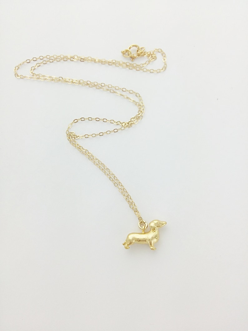 May include: A gold chain necklace with a small gold dachshund pendant.