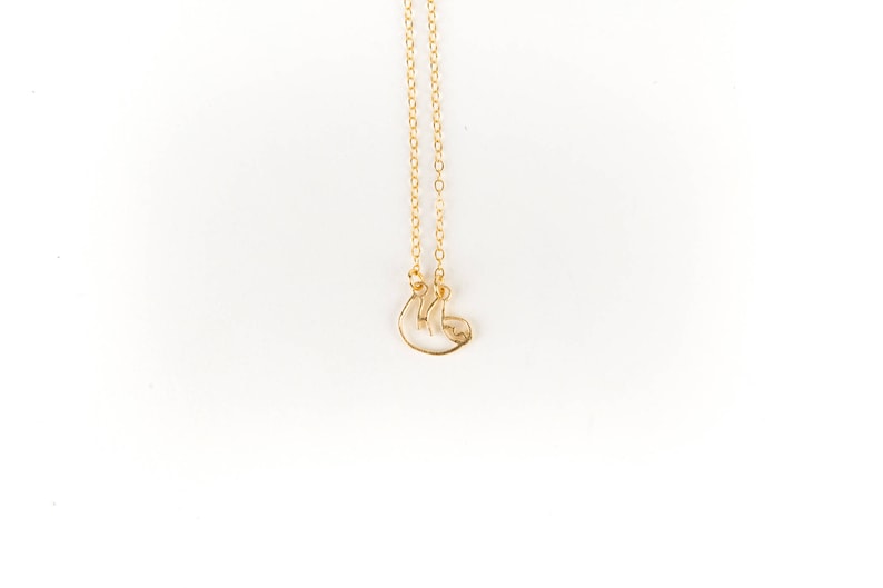 May include: A gold chain necklace with a delicate, wire-shaped sloth pendant.