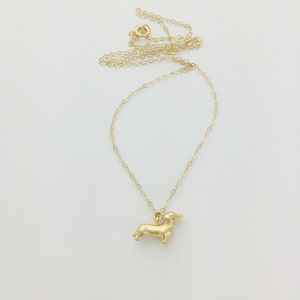 May include: A gold chain necklace with a small, gold dachshund pendant.