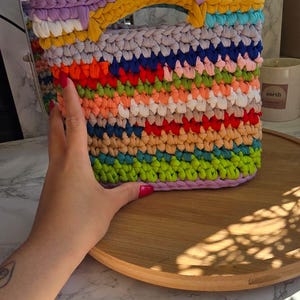 May include: A white ceramic mug with a black handle and the text "But First, Coffee" in a black, handwritten-style font. The mug is on a white surface.