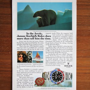May include: An advertisement featuring a Rolex watch with a blue and red bezel, a polar bear and cub on an iceberg, and text about Arctic exploration. The watch has a stainless steel band.