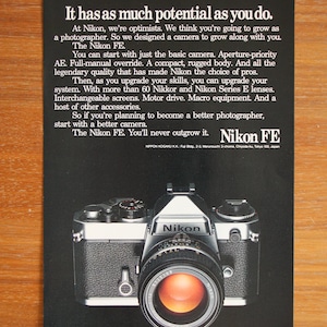 Peut inclure: Publicité pour l'appareil photo Nikon FE. L'image montre un appareil photo noir et argenté avec un grand objectif. Le texte sur l'annonce indique "It has as much potential as you do." et "Nikon FE."