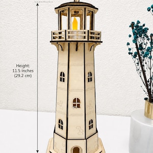 May include: A laser-cut wooden lighthouse model with a yellow LED light at the top. The structure features multiple windows and a balcony. It measures 11.5 inches in height and 5.8 inches in width, as indicated by the text labels on the image.