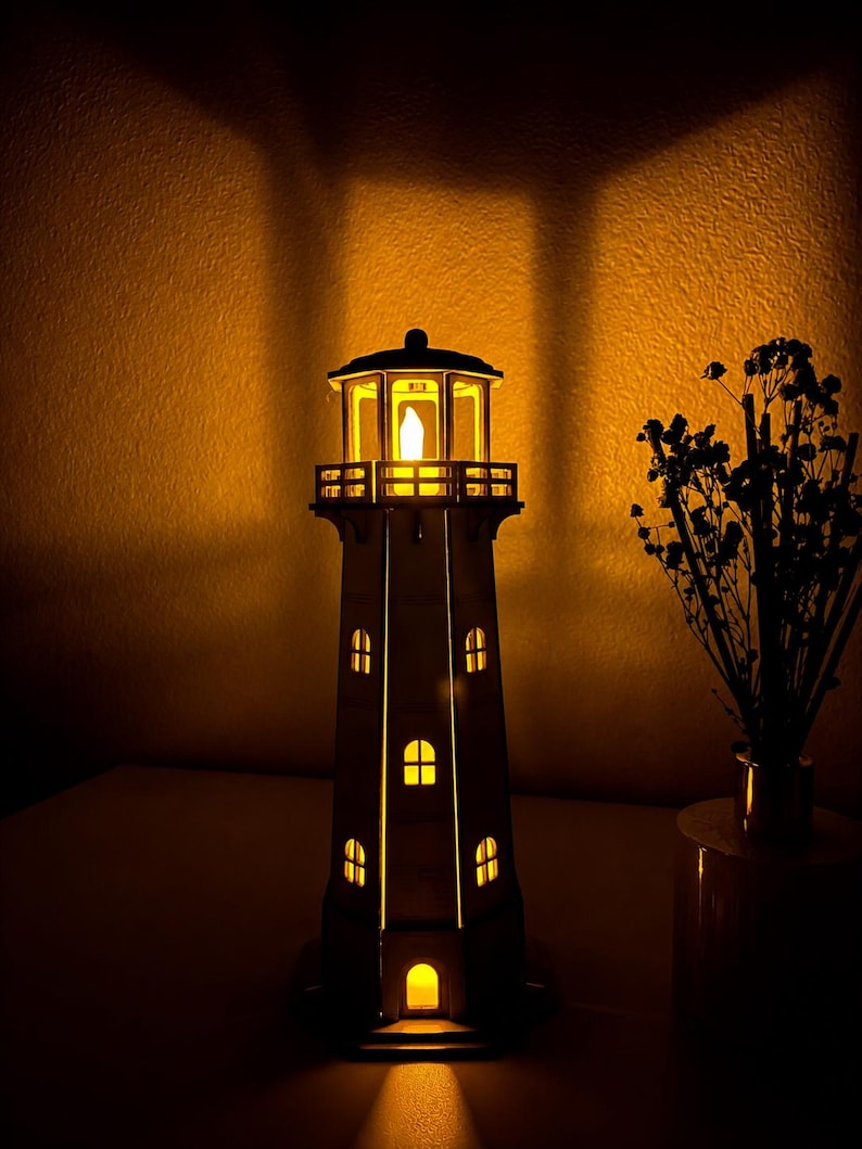 May include: A vertical lighthouse lamp featuring a light-colored structure with multiple arched windows and a lantern room at the top. The lamp emits a warm, glowing yellow light from within, casting a bright illumination through the openings.