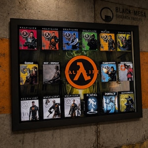 Può includere: Una cornice nera contenente una collezione di copertine di videogiochi in miniatura, inclusi titoli come Half-Life, Portal, Team Fortress e Counter-Strike, centrata attorno a un grande logo circolare arancione e nero di Half-Life.