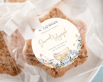 Puede incluir: Galletas en forma de estrella en envase transparente, atadas con una cinta blanca. Una etiqueta redonda presenta diseños florales y texto en inglés y árabe, incluyendo "Dawood's Aqeeqah" y "Thank you for coming to."