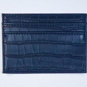 Puede incluir: Un tarjetero azul marino con un patr&oacute;n texturizado similar al de un cocodrilo. La cartera rectangular tiene m&uacute;ltiples ranuras y est&aacute; hecha de un material duradero. El tarjetero es un accesorio elegante.