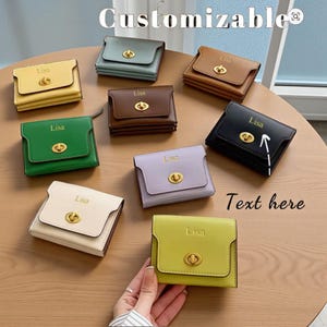 May include: A collection of small, square wallets in various colors, including yellow, green, brown, and black. Each wallet features a gold-colored clasp and the name "Lisa" embossed on the front. The word "Customizable" is at the top.
