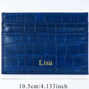 Puede incluir: Tarjetero azul con textura de cocodrilo, de 10,5 cm por 7,5 cm. El nombre "Lisa" est&aacute; impreso en dorado en la parte delantera. Cuenta con m&uacute;ltiples ranuras para tarjetas. Dimensiones aproximadas: 4,133 pulgadas por 2,952 pulgadas.