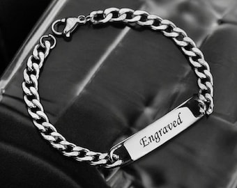 Könnte beinhalten: Ein silberfarbenes Armband mit einem Panzerketten-Design. Das Armband hat eine rechteckige Platte mit dem Wort "Engraved" graviert. Das Armband besteht aus glänzendem Metall.