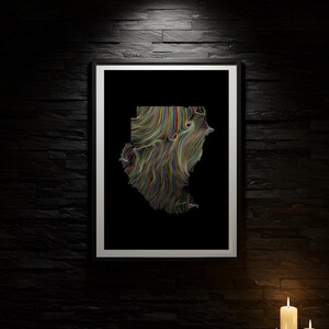 May include: A framed art print with an abstract design in a geographical shape, featuring swirling lines of various colours. The artwork is set against a black background with a white border, mounted on a dark, textured wall. Three lit candles are in the foreground.
