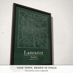 Three-quarter view of the framed Chalkboard City Map poster on a white plaster wall