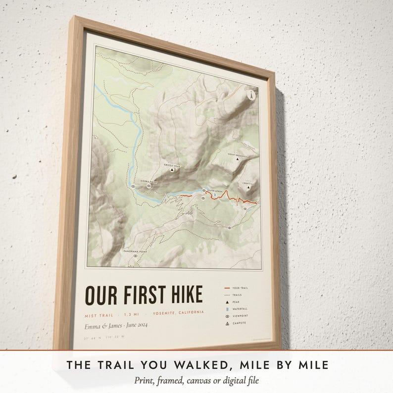 Three-quarter view of the framed Hiking Trail Map poster on a white plaster wall