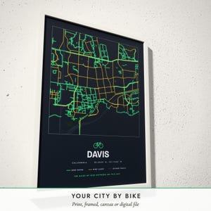 Three-quarter view of the framed Bike City Map poster on a white plaster wall