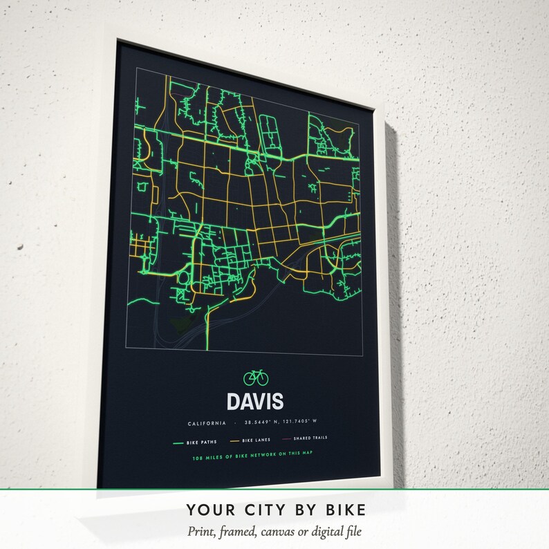 Three-quarter view of the framed Bike City Map poster on a white plaster wall