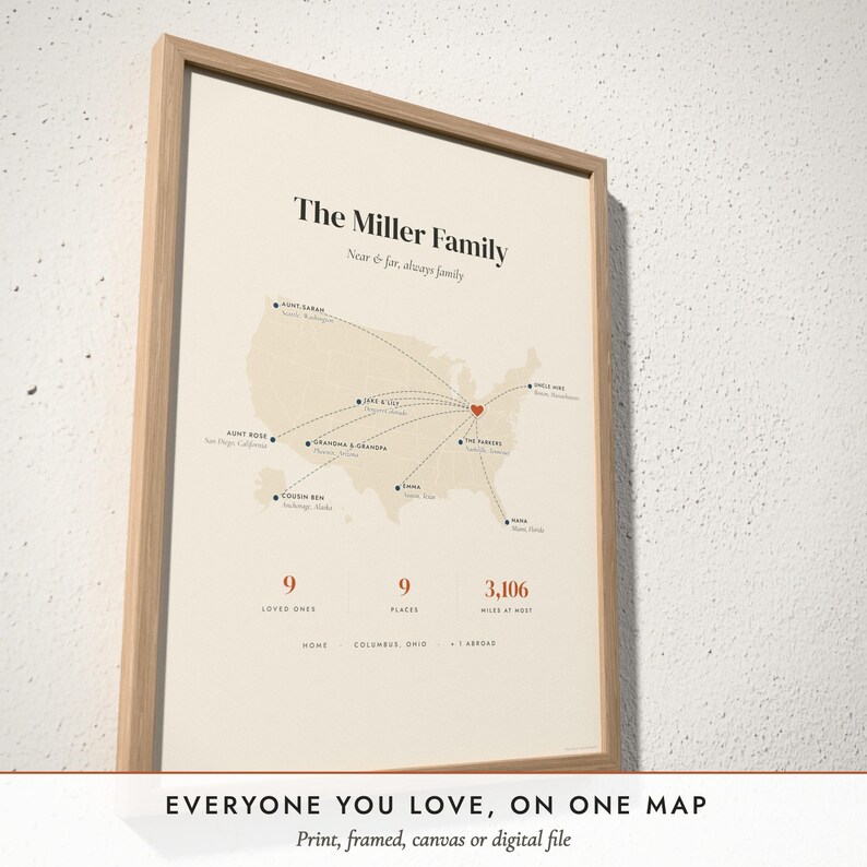 Three-quarter view of the framed Family Near & Far Map poster on a white plaster wall