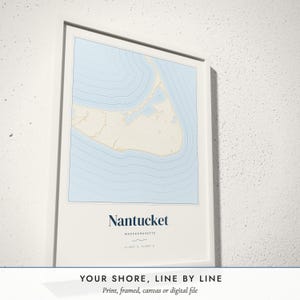 Three-quarter view of the framed Coastal Contour Map poster on a white plaster wall