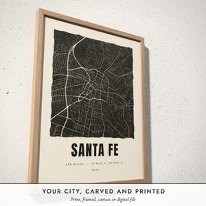 Three-quarter view of the framed Linocut City Map poster on a white plaster wall