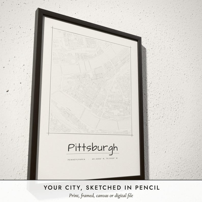 Three-quarter view of the framed Pencil Sketch City Map poster on a white plaster wall