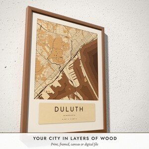 Three-quarter view of the framed Layered Wood City Map poster on a white plaster wall