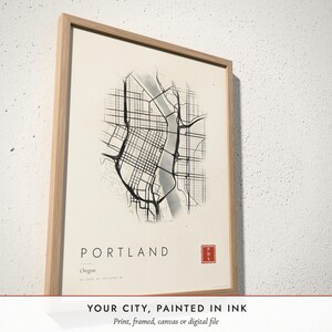 Three-quarter view of the framed Ink Wash City Map poster on a white plaster wall