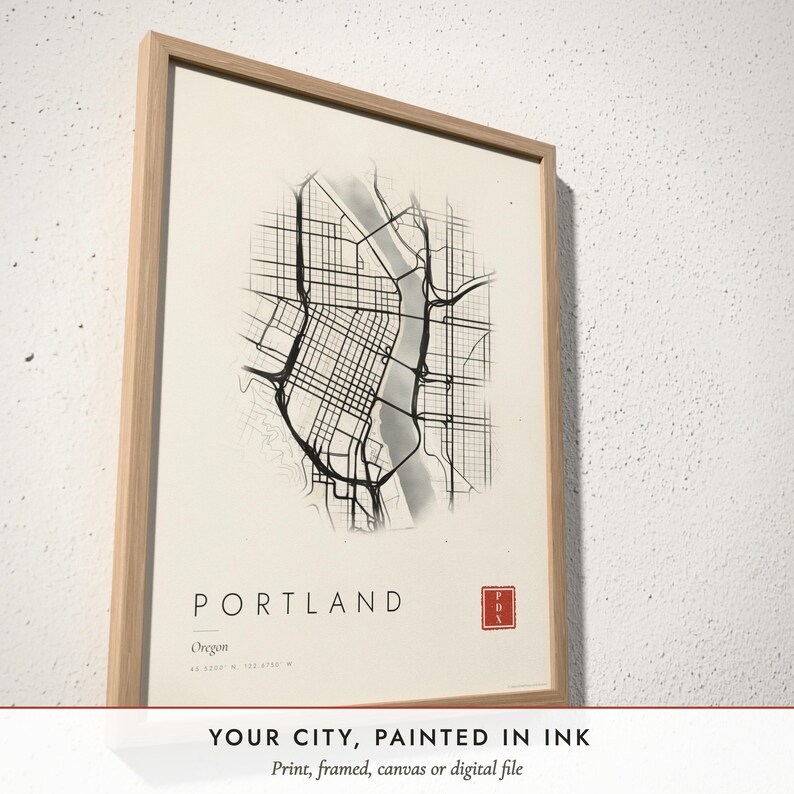 Three-quarter view of the framed Ink Wash City Map poster on a white plaster wall
