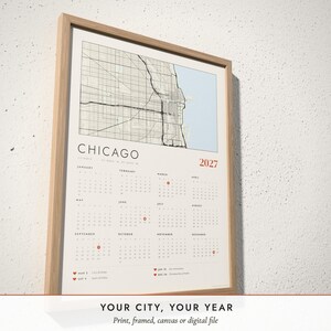 Three-quarter view of the framed Map Calendar 2027 poster on a white plaster wall