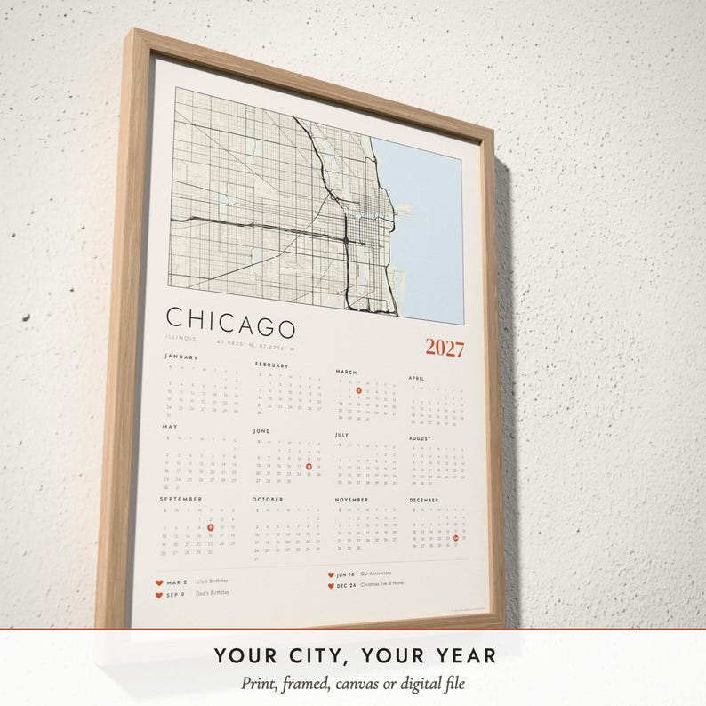 Three-quarter view of the framed Map Calendar 2027 poster on a white plaster wall