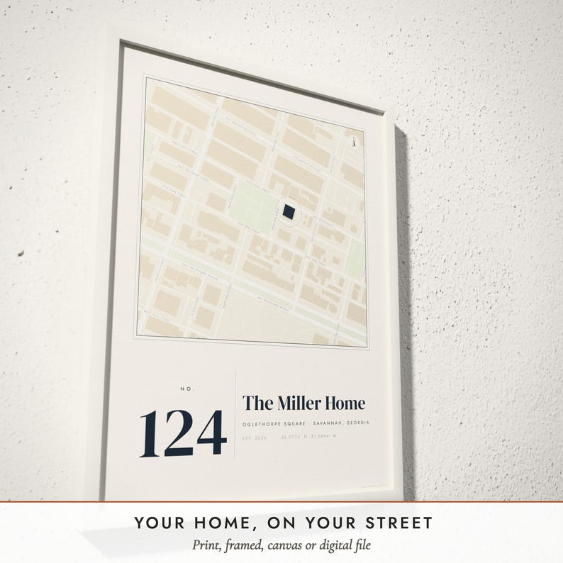 Three-quarter view of the framed Our Home Map poster on a white plaster wall