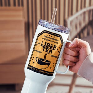 Könnte beinhalten: Weißer isolierter Becher mit Henkel und klarem Strohhalm. Der Becher hat ein Etikett mit dem Text "LIBER TEA" in einem schwarz-goldenen Design, mit dem Satz "Freedom-Infused" darüber und "Every Sip a Strategic Victory" darunter.